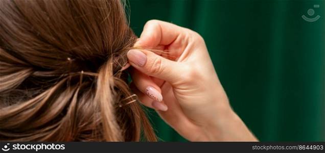 Hairdresser makes hairstyles for a young woman in beauty salon close up. Hairdresser makes hairstyles for a young woman in beauty salon close up.