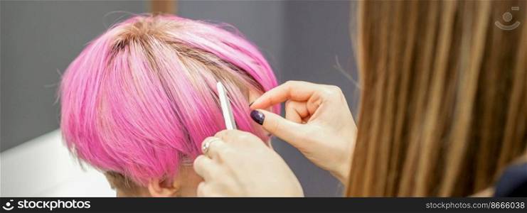 Hairdresser prepares dyed short pink hair of a young woman to procedures in a beauty salon. Hairdresser prepares dyed short pink hair of a young woman to procedures in a beauty salon.