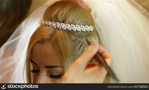 Hairdresser putting on bridal veil