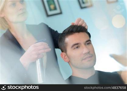 hairdresser sprays a handsome client
