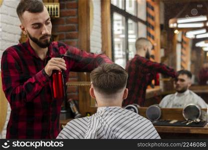 hairdresser sprinkling young mans hair