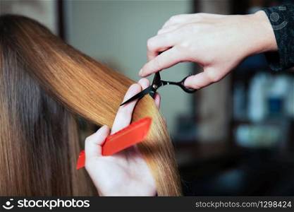 Hairdresser with scissors and comb cute hair to young woman.. Hairdresser cute hair to young woman.
