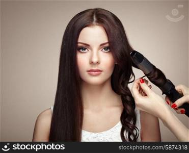 Hairdresser woman curls her hair. Portrait of young beautiful girl with luxurious hair. Fashion and beauty. Perfect make-up