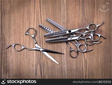 hairdressing equipment like different scissors on brown wooden table in professional hairdressing salon