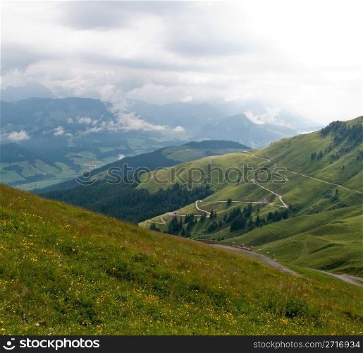 Hairpin bends on road up the grassy slopes on cloudy day in Switzerland