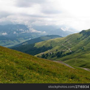 Hairpin bends on road up the grassy slopes on cloudy day in Switzerland