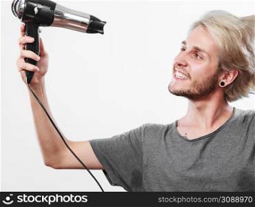 Hairstyle and fashion. Young trendy male hairstylist barber with new idea of look changing. Blonde man holding hair dryer and comb creating new hairdo. Young man drying hair with hairdryer