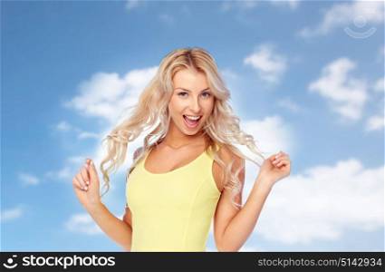 hairstyle and people concept - happy smiling beautiful young woman with blonde hair over blue sky and clouds background. happy young woman with blonde hair over blue sky