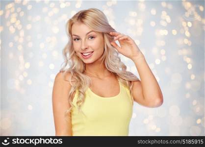hairstyle and people concept - happy smiling beautiful young woman with blonde hair over holidays lights background. happy smiling young woman with blonde hair
