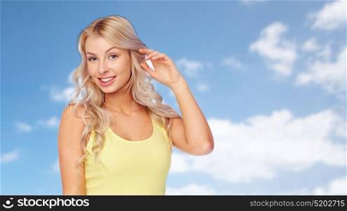 hairstyle and people concept - happy smiling beautiful young woman with blonde hair over blue sky and clouds background. happy smiling young woman with blonde hair