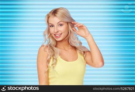 hairstyle and people concept - happy smiling beautiful young woman with blonde hair over ribbed blue background. happy smiling young woman with blonde hair