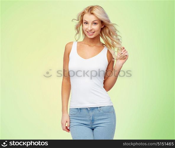 hairstyle, fashion and people concept - happy smiling beautiful young woman in white top and jeans with blonde hair over green background. happy smiling young woman with blonde hair