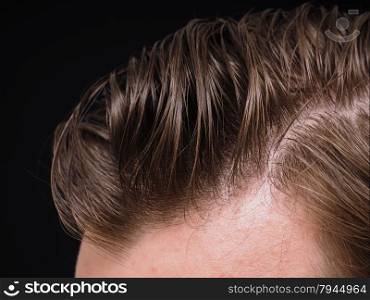 Hairstyle on male person with brown hair at closeup isolated towards black background