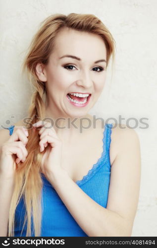 Hairstyle. Portrait of blond woman teenage girl plaiting braid hair. Indoor.