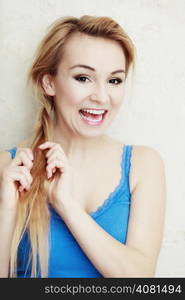 Hairstyle. Portrait of blond woman teenage girl plaiting braid hair. Indoor.