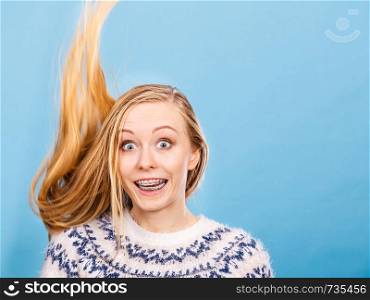 Hairstyles ideas, happiness concept. Crazy teenage woman wearing winter jumper with windblown blonde hair. Crazy blonde woman with windblown blonde hair