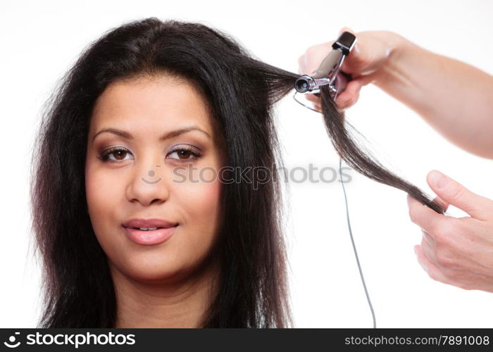 Hairstyling. attractive mixed race woman with long hair making hairstyle hairdo with electric hair curler iron on white