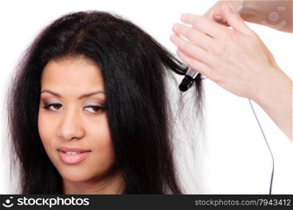 Hairstyling. attractive mixed race woman with long hair making hairstyle hairdo with electric hair curler iron on white