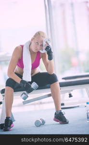 halethy young woman exercise with dumbells and relaxing on banch in fitness gym. young woman exercise with dumbells