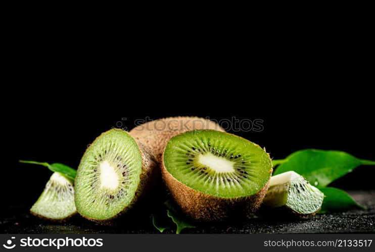 Half a juicy kiwi on the table. On a black background. High quality photo. Half a juicy kiwi on the table.