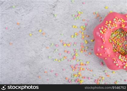 Half a strawberry donut decorated icing and sprinkling on the floor