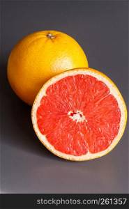 Half and whole grapefruits on a gray background