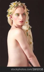 Half Body Shot of a Naked Pretty Young Woman with Flowers on her Long Blond Hair, Looking Into the Distance Against Black Background.