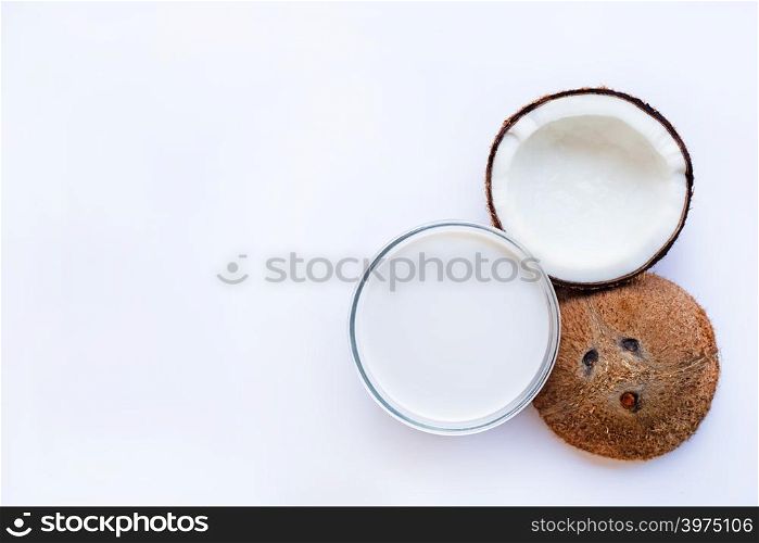 Half Coconut with glass bowl of coconut milk on white background.