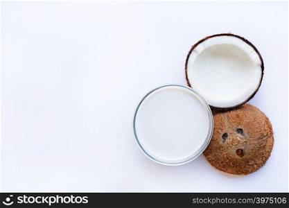 Half Coconut with glass bowl of coconut milk on white background.