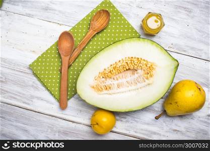 Half cut melon with honey and pears on wood in rustic style
