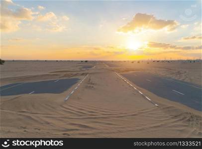 Half desert road or street with sand dune in Dubai City, United Arab Emirates or UAE. Natural landscape background at sunset time. Famous tourist attraction. Top view.