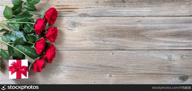 Half dozen red roses and gift box on left hand side of rustic wood in flat lay view