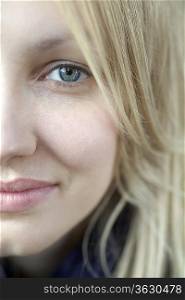 Half face of smiling blonde woman with blue eyes