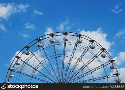 Half Ferris wheel on blue sky and white clouds