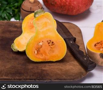 half fresh pumpkin and knife on a wooden kitchen board