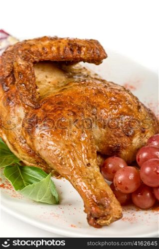 Half grilled chicken closeup with grape and greens on a white