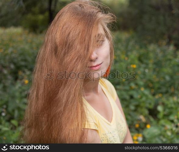 Half-hide by hair shot of the blonde female outdoors. Head and shoulders. Sunner time fun