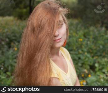 Half-hide by hair shot of the blonde female outdoors. Head and shoulders. Sunner time fun