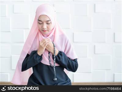 Half length front view of asian young beautiful muslim woman prayer dress hijab hand hold beads pray meditation in mosque for eid mubarak life and soul fasting of international islamic ramadan Namaz.
