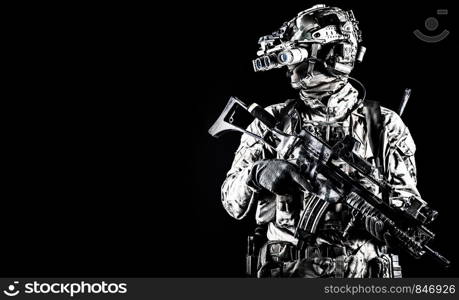 Half length portrait of army special forces rifleman, commando elite soldier equipped radio tactical headset, armed service rifle, using night vision goggles in darkness, isolated on black, copyspace. Soldier in night vision device on black background