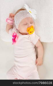 Half-length portrait of two months sleeping girl. a two-month baby girl Europeans on the back with a bandage on his head with a flower lying on a soft bed