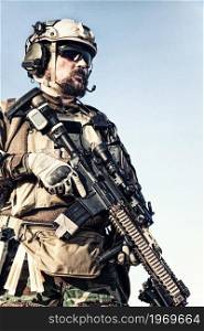 Half length portrait of U.S. marine riders, special forces soldier, experienced commando in helmet and ballistic goggles, equipped tactical radio headset, holding service rifle with optical sight. Marines marksman armed service rifle with optics