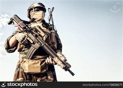 Half length portrait of U.S. marine riders, special forces soldier, experienced commando in helmet and ballistic goggles, equipped tactical radio headset, holding service rifle with optical sight. Marines marksman armed service rifle with optics