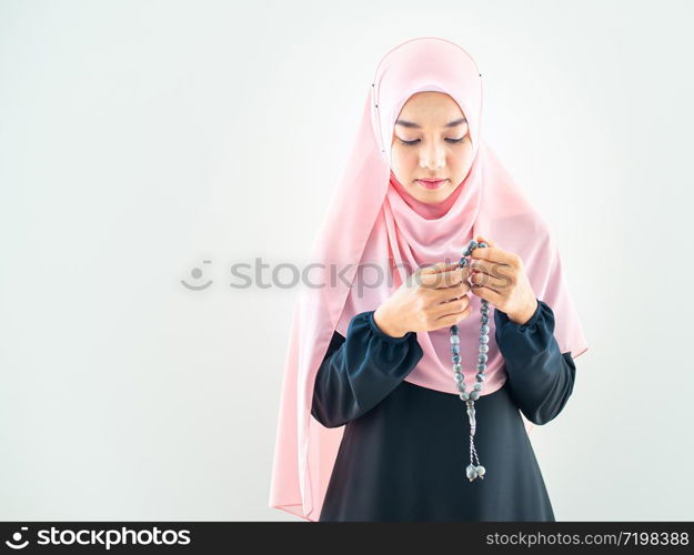 Half length side view of asian young beautiful muslim woman prayer dress hijab pray meditation in mosque for eid mubarak life and soul fasting of international islamic ramadan Namaz.