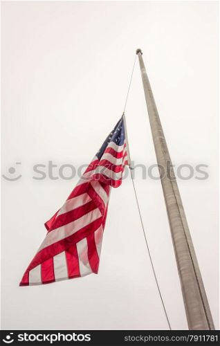 Half mast American flag concept as a symbol of the United States flying at low level to honor respect and mourning for fallen heroes.