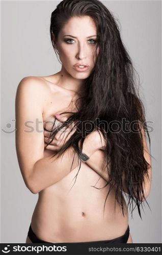Half naked brunette woman wearing panties with very long curly hair on white background. Studio shot