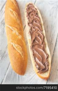 Half of baguette with chocolate cream on the wooden table