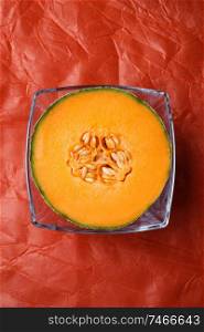 half of cantaloupe melon around orange background. tasty sweet exotic fruit