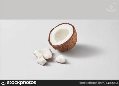 Half of fresh ripe organic tropical coconut fruit on a light grey duotone background with soft shadows and copy space. Vegan concept.. Fresh half of ripe organic tropical coconut fruit on a light grey background.
