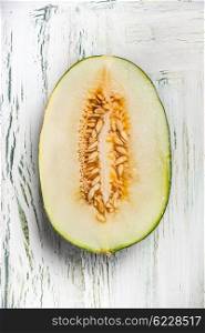 Half of melon with seeds on light rustic background, top view